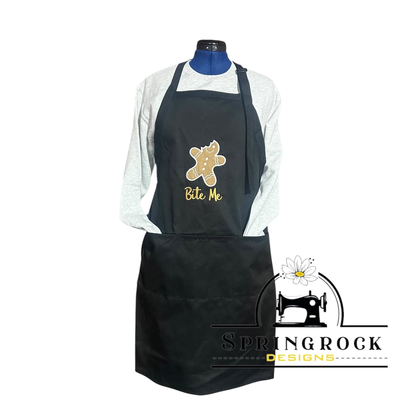 Black apron with a gingerbread man design and ' Bite Me' text on a mannequin, branded with Springrock Designs.